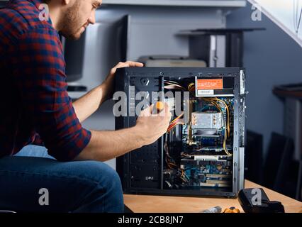 specialised computer repair technician testing an old system unit, close up side view photo Stock Photo
