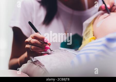 Bunch of artificial eyelashes in tweezers. Extensions of artificial eyelash, process close up. Woman in a beauty salon. Beauty and self-care. Stock Photo