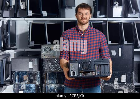 cheerful attractive man holding a system unit and looking at the camera, close up photo, small business, pastime Stock Photo