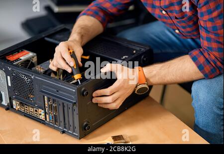 man assembling computer system unit. close up cropped photo. engineer with a screwdriver at work Stock Photo