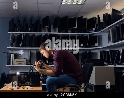 awesome guy concentrated on working with wires in the computer office, close up side view photo Stock Photo