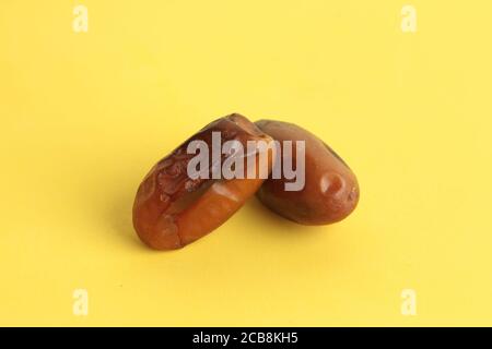 High angle shot of two dried dates isolated on a yellow surface Stock Photo