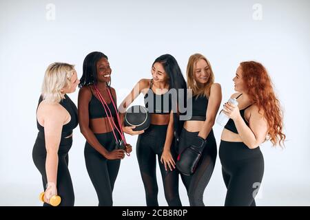 Young fitness girls in sportive clothes laughing, look at each other. Portrait og beautiful girls. different nations, sizes, colors. Healthy lifestyle Stock Photo