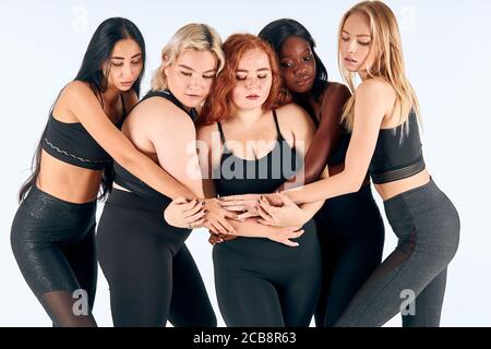Portrait of slim different girls standing together and hug. Multinational, multiethnic group of girls Stock Photo