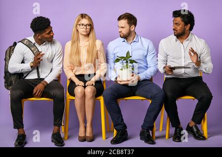 diverse multinational group of people sitting together and looking at each other waiting for job interview Stock Photo