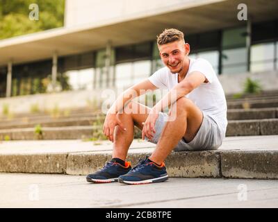 Young Caucasian man sitting on the stairs in the park Stock Photo