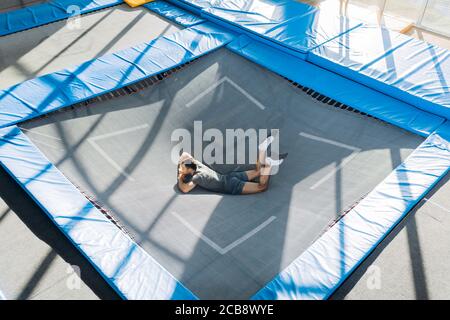 funny guy lying on the trampoline and having a rest after intensive jumping. full length photo. break time Stock Photo