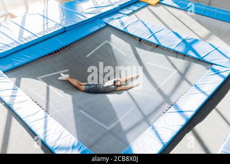 fit man lying on the bounce mat. full length portrait.gymnastics, trampoline workout Stock Photo