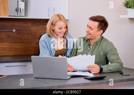 spouses sitting with laptop and documents, analyzing paperwork and house utility bills, financial issues, thoughtful couple consider papers managing f Stock Photo