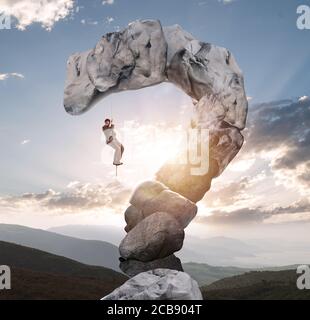 Businessman tries to climb with difficulty on a mountain shaped as question mark Stock Photo