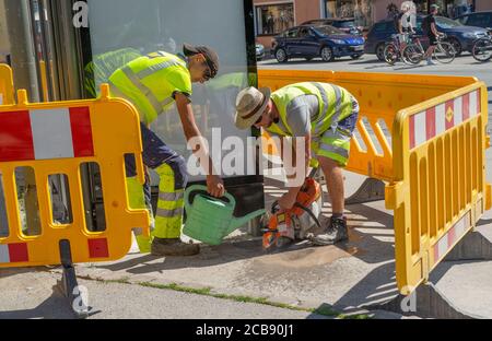 Innsbruck Austria July 27 2020: Workers who are cutting the concrete with the hose, wet the blade to avoid dust Stock Photo