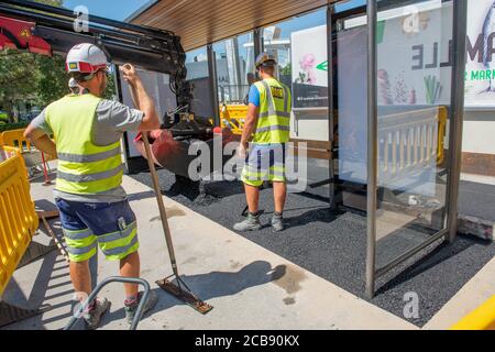 Innsbruck Austria July 27 2020: Workers at work asphalting tram stop with rake and shovel Stock Photo