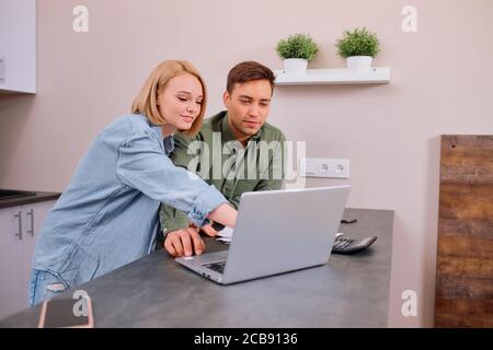 spouses sitting with laptop and documents, analyzing paperwork and house utility bills, financial issues, thoughtful couple consider papers managing f Stock Photo