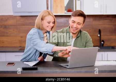 spouses sitting with modern laptop and documents, analyzing paperwork and house utility bills, young couple consider papers managing finances and expe Stock Photo
