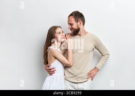 girl with long brown hair putting her arms on her guy's shoulder, relies on him, relationship between wife and husband , isolated white background Stock Photo