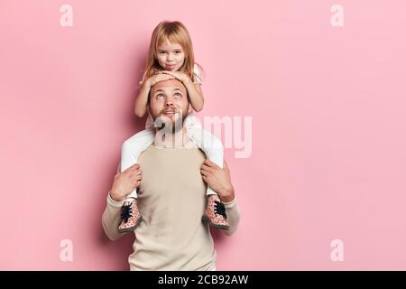 young good looking kind fatherhaving fun with his little child, close up portrait, isolated pink background, studio shot. family, happy parenthood Stock Photo