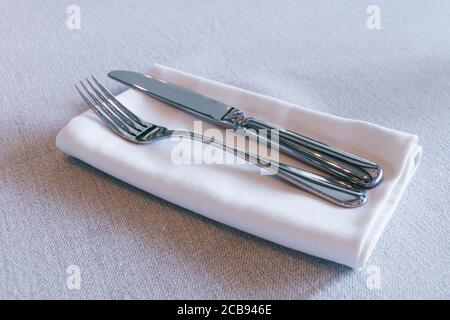 restaurant cutlery, knife and fork on a table with white napkin Stock Photo