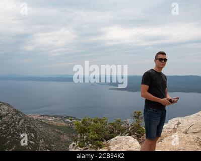 Young adult man posing on top of the Vidova gora mountain, highest point of the island Brac. Popular spot for tourists to taking photos Stock Photo