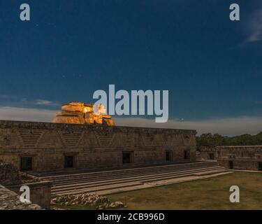 The Pyramid of the Magician behind the east building of the Nunnery Quadrangle it is lit in the pre-Hispanic Mayan ruins of Uxmal, Mexico. Stock Photo