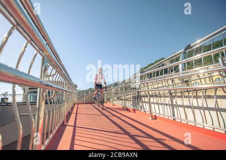 Man on bicycle riding bridge in afternoon Stock Photo