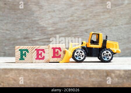 Toy bulldozer hold letter block e to complete word fee on wood background Stock Photo