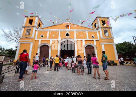 Ometepe Island / Nicaragua - July 15, 2019: Wide angle shot of people entering yellow church in Moyogalpa village Stock Photo