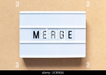 White lightbox with word merge on wood background Stock Photo
