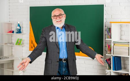 loving mathematics. become good at math. stem in classroom. senior man teacher use tool at blackboard. bearded tutor in glasses. back to school. protractor ruler. learn geometry easily. Stock Photo