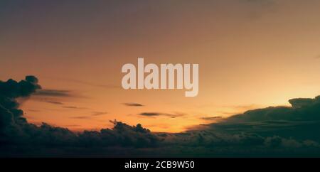 Beautiful golden sunset sky and dark clouds. Sky in the evening with yellow and orange light from the sun. Peaceful and tranquil background. Beauty in Stock Photo
