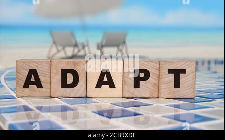 ADAPT Word on wooden blocks standing on swimming pool borders mosaic near the beach. Business change concept Stock Photo