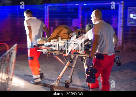 Hamburg, Germany. 12th Aug, 2020. A mother lies on a stretcher with her newborn child in her arms and is pushed by rescue workers. A woman under the influence of drugs gave birth to a child in front of the Millerntor stadium in Hamburg-St. Pauli during the night to Wednesday. A police spokesperson said that police and rescue workers had helped with the fall birth. Credit: Jonas Walzberg/dpa - ATTENTION: The woman and the baby were pixelated for legal reasons/dpa/Alamy Live News Stock Photo