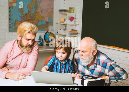 Happy man family using notebook together. Son teaching father and mature senior grandfather to use laptop computer. Stock Photo