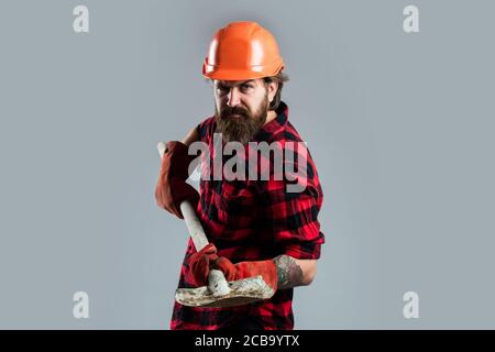 He needs a little break. confident construction engineer. professional architect hold shovel in gloves. repair and building. serious worker wear hard hat. brutal builder in helmet. bearded repairman. Stock Photo