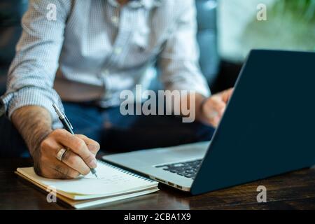 Asian businessman Write notes and using laptop for working in home office. Stock Photo