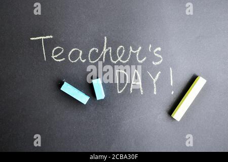 Flat lay composition inscription TEACHER'S DAY on black chalkboard and pieces of chalk Stock Photo
