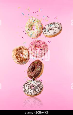 Flying sweet donuts isolated on pink background. Concept of low gravity food in freeze motion effect. High resolution image Stock Photo