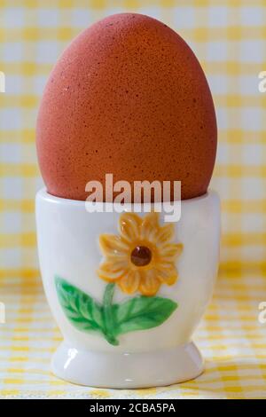 M&S British Farmed Free Range Maran Island Brown Egg in eggcup egg cup on yellow & white checked napkin serviette Stock Photo