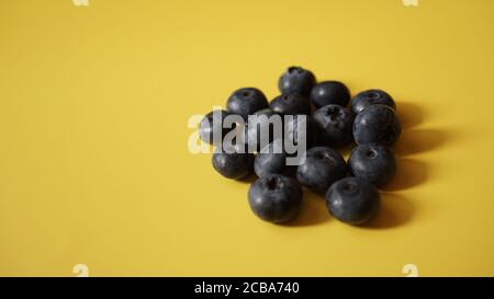 Delicious fresh blueberry on yellow background, space for text Stock Photo