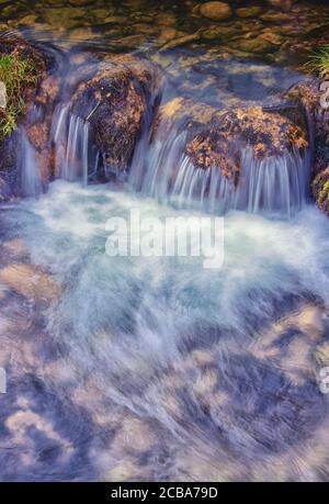 Gently flowing water over submerged stones on a small riverbed Stock Photo