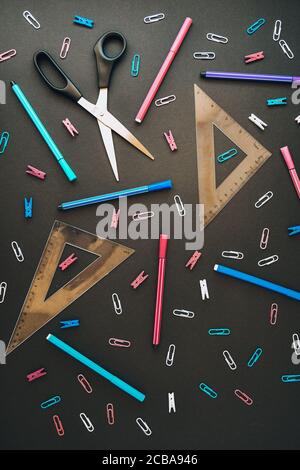 Flat lay composition with scissors ruler and school supplies on dark background. Stock Photo