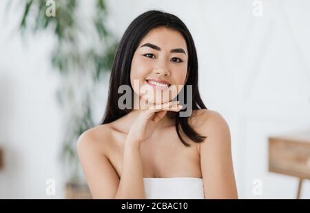 Young asian woman with perfect skin touching her chin Stock Photo