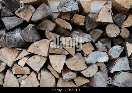 full-frame shot of stack of firewood, wood billets against wooden wall background Stock Photo