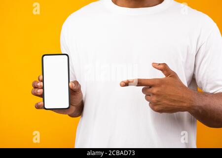 Black Man Showing Smartphone With Blank Screen, Yellow Background Stock Photo