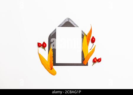 Top view composition of black blank post mail envelope mock up with a autumn yellow and red leaves background Stock Photo