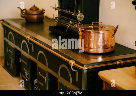 A large copper pot and teapot on an antique table with an original design with wrought iron patterns and a metal handrail. Stock Photo