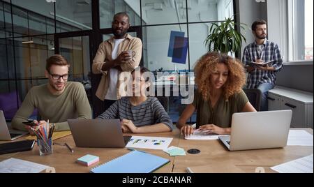 Brainstorming. Succesful business team, group of happy multiracial coworkers sharing ideas, working on project together while sitting in the modern Stock Photo
