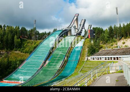 Lahti, Finland - 4 August 2020: Lahti sports centre with three ski jump towers. Sportsman is jumping from the smallest ski jump tower. Stock Photo