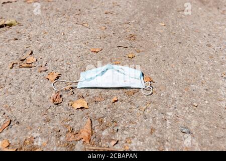 Used protective medical mask dumping on the city ground. Coronavirus, Covid-19 and Environmental pollution. Stock Photo
