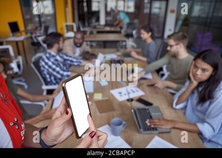 Business meeting. Young multicultural business people working in the modern office, having a meeting in conference room. Focus on woman pointing at Stock Photo