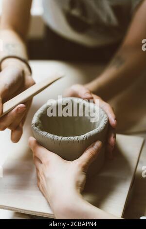Woman making ceramic pottery, four hands close-up, focus on potters, palms with pottery Stock Photo